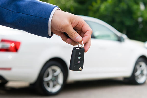 A person handing out a key to a car