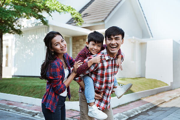 A mother, father, and child smiling in front of a home